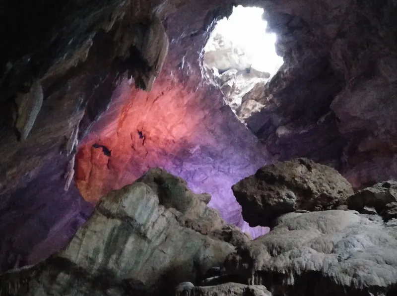 Coloured lights and a skylight inside a limestone cave at Borra Caves
