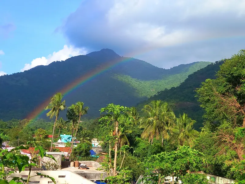 A rainbow over forested hills above a village in Araku Valley