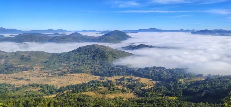 Clouds filling the valleys between green hills, seen from the Vanjangi hills near Paderu